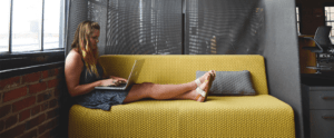 vrouw op bank in huiskamer met laptop