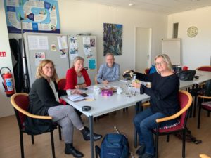 een man en drie vrouwen aan een tafel. een vrouw schenkt champagne in
