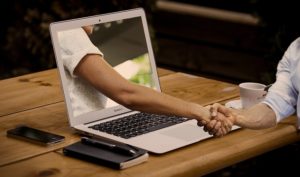 hand die door het scherm van een laptop steekt