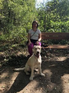 Jonge vrouw met Hond op bankje in het bos