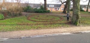 Man op een grasveld die een smiley van bladeren maakt