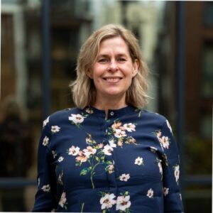 vrouw met halflang donkerblond haar en een jurk met bloemetjes