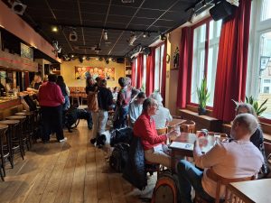 Groep mensen in een cafe met elkaar in gesprek.